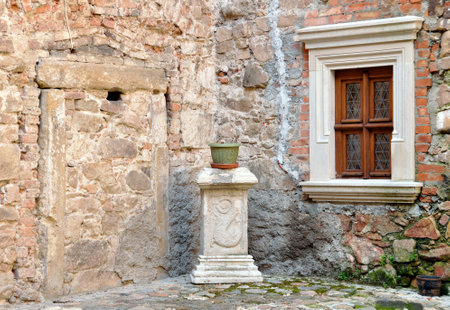 Corners of the medieval wall of the building with a window and a pot on the pedestal. Czarne, Poland.の写真素材