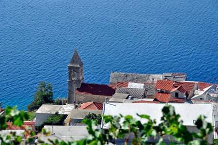 A view from above of a fragment of a small town with a church, against the background of a blue, calm sea. Adriatic Sea, Croatia, Pisak.の写真素材