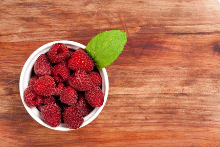 Bowl of raspberries on an old wooden table