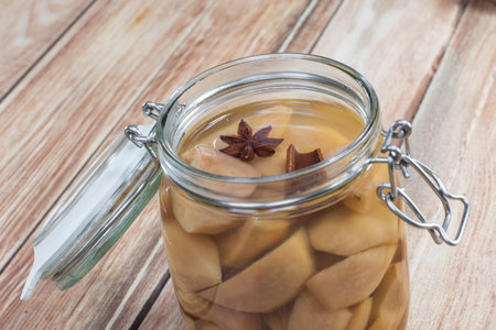 Preserved Pear Compote with Star Anise and Cinnamon in Glass Jar on Wooden Backgroundの写真素材