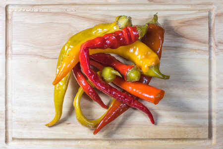 Top View on Preserved Pickled Chilli Peppers on a Wooden Chopping Board