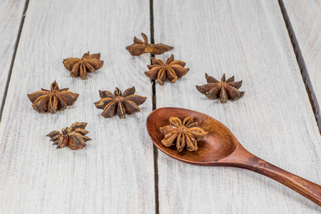Star Anise on a Wooden Spoon on White Wooden Tableの写真素材