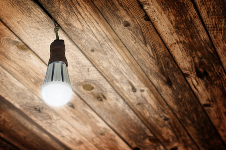 New Shining LED Light Bulb installed in an Old Socket to E27 Light Bulbs on Wooden Ceilingの写真素材