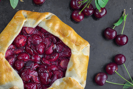 Top View on Delicious Rustical Sour Cherry Pie on Black Background with a few sour cherriesの写真素材