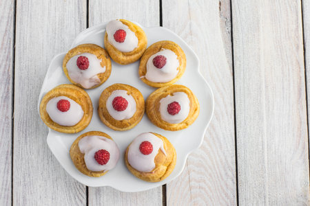 Top View on Raspberries Profiterole with White Chocolate on Plate on White Table