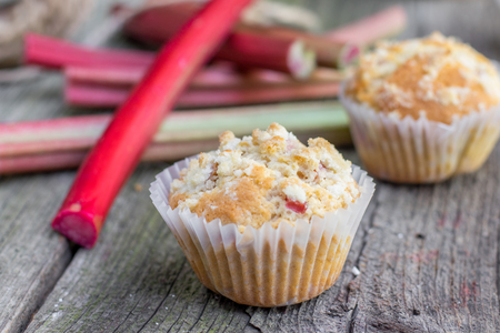 Detail on a Rhubarb muffin with rhubarb petioles in the background on Old Wooden Boardの写真素材