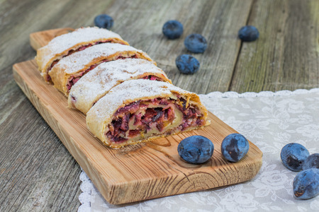 Plum strudel on wood plank timber with fresh plums on a old wooden boardの写真素材