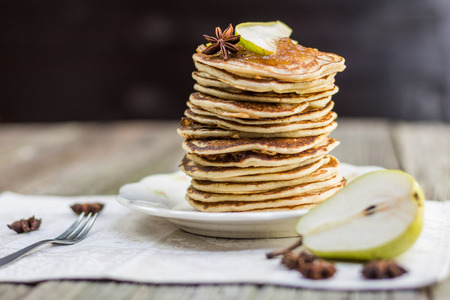 Whole grain pancakes with pear jam and a slice of pear and star anise on set table on old wooden board
の写真素材