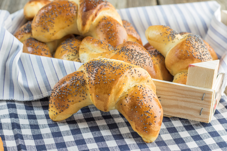Gold Poppy seed croissant on white-blue clothtableの写真素材