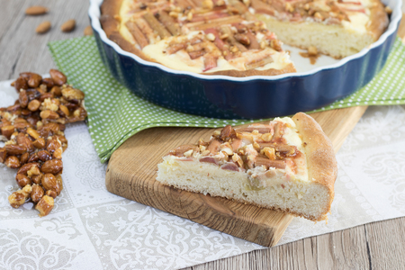 Slice of Rhubarb cake with caramelized almond krokant on wooden boardの写真素材
