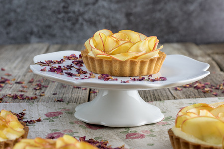 Apple tartelette on a white plate with caramel glaze on a old boardの写真素材