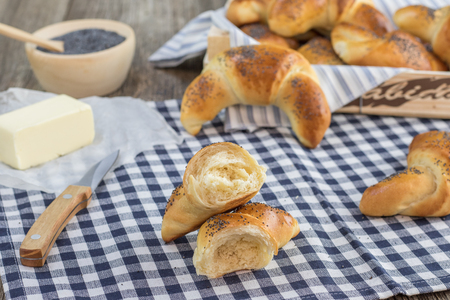 Halver poppy seed croissant with butter on white-blue clothtableの写真素材