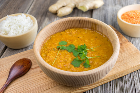 Indian lentil dhal with ginger and fresh coriander on a wooden boardの写真素材