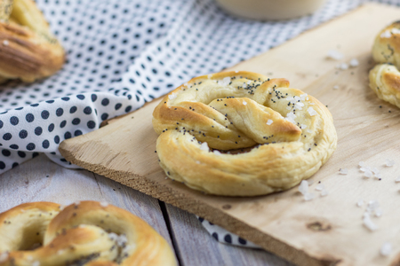 Detail on a one Pretzel with salt and poppy seeds on a wooden boardの写真素材