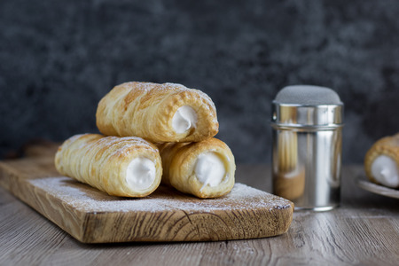 Three puff pastry creme rolle with cream (traditional Czech dessert) on wooden boardの写真素材