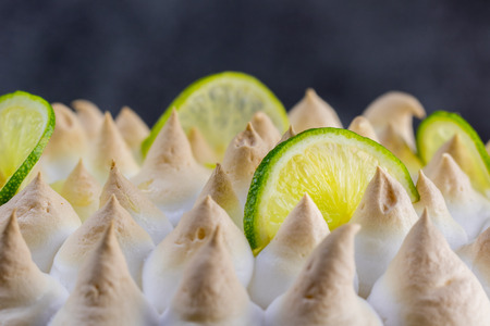 Lime meringue cake with slices of lime with dark background - detail viewの写真素材