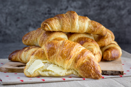 Gold butter croissant greased with butter on natural wood plank with marble backgroundの写真素材