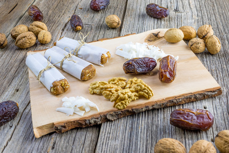Three Dates bar wrapped in paper with walnuts and coconut on a wooden boardの写真素材