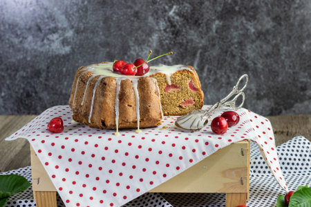 curd cheries cake with lemon topping with confectionery tongs on tablecloth with red polka dots