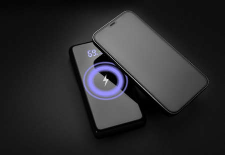 Wireless charging. Wireless power bank charging phone on black background. Modern technology.の写真素材