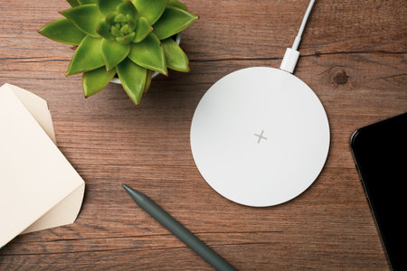 Wireless charger on a wooden office desk. Top view.
