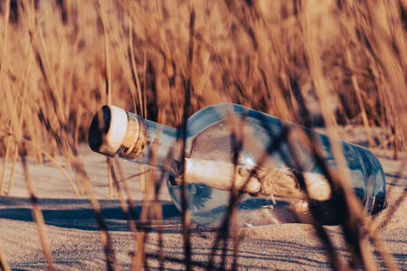 Message in a bottle on the beach at sunset. Conceptual image.の写真素材