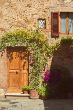The doors in the medieval town surrounded by plants and colorful flowers, Pienza, Italyの写真素材