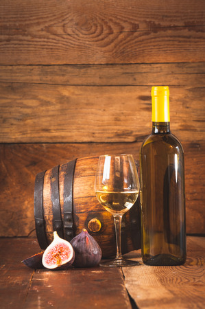 Barrel of white wine with bottle, glass and figs on a rustic table.の写真素材