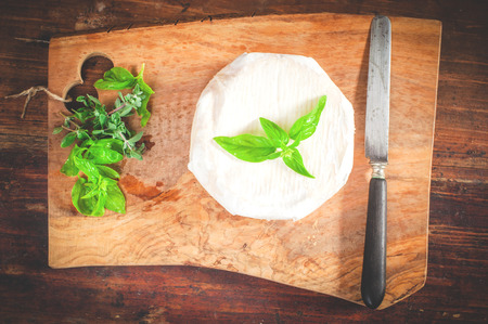Smelly blue cheese on a wooden rustic table with knife and basilの写真素材