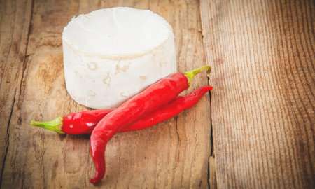 Smelly blue cheese on a wooden rustic table with hot chili pepperの写真素材