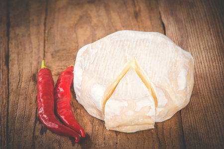 Smelly blue cheese on a wooden rustic table with hot chili peppersの写真素材