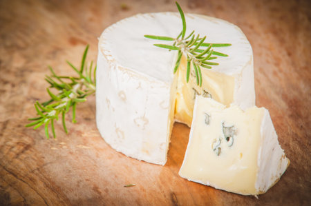 Smelly blue cheese on a wooden rustic table with rosemary and salamiの写真素材