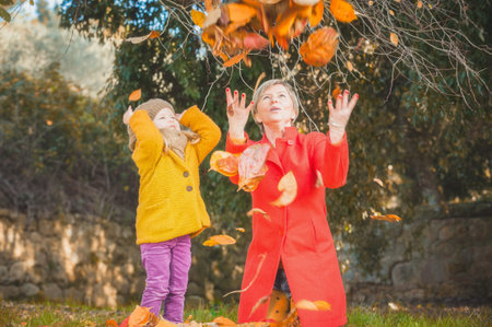 Beautiful girl, smiling blonde plays with the autumn leaves
