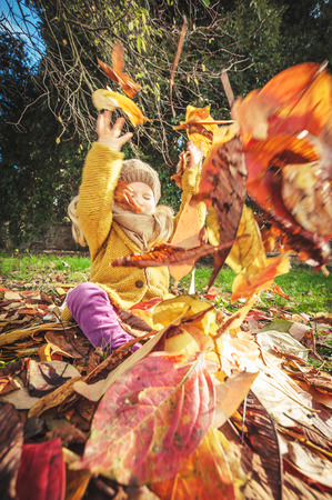 Beautiful girl, smiling blonde plays with the autumn leavesの写真素材