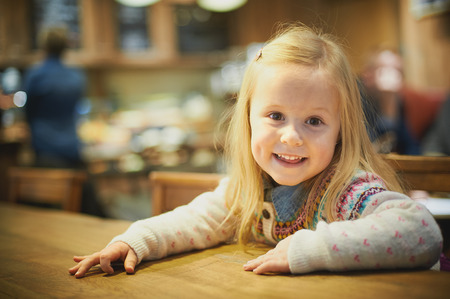 Little blond girl in a cafe drinking hot milkの写真素材