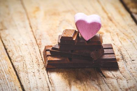 Pink heart on a black chocolate with rustic wooden backgroundの写真素材