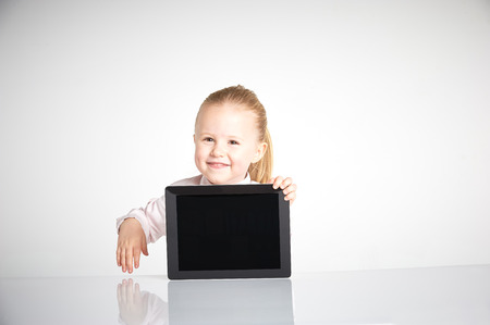 Cute little and smiling girl plays with a tabletの写真素材