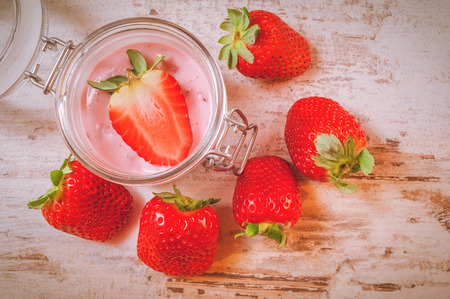 Spring fruits, strawberries with strawberry yogurt on a vintage wooden table.の写真素材