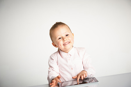 Cute little and smiling girl plays with a tabletの写真素材