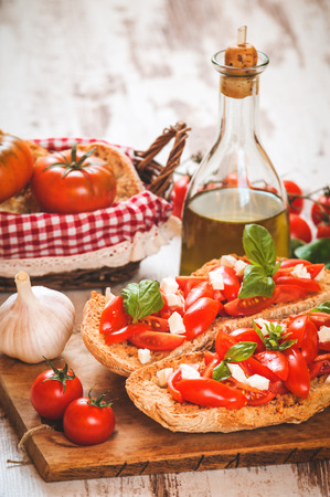 Italian starter, bruschetta with Sicilian red fresh tomato and mozerella cheese on a wooden backgroundの写真素材