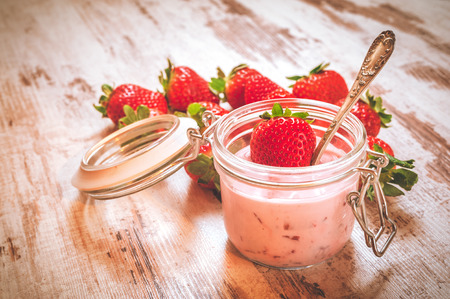 Spring fruits, strawberries with strawberry yogurt on a vintage wooden table.の写真素材