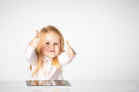 Cute little and smiling girl plays with a tabletの写真素材