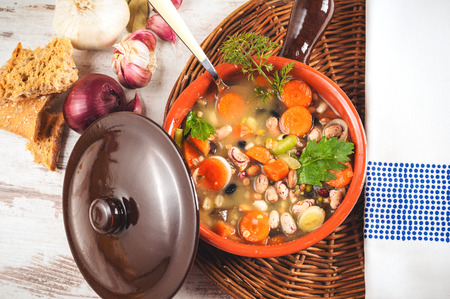 Rural vegetarian broth soup with colorful vegetables and rustic clay pot.の写真素材