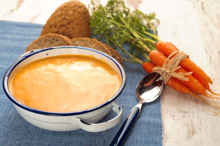 Soup with pumpkin and carrot on a blue tablecloth in country style
