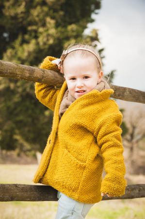 Smiling little girl on a wooden fenceの写真素材