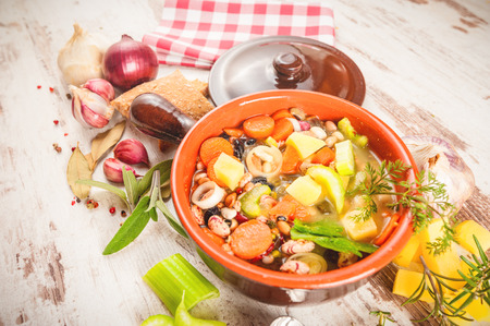 Rural vegetarian broth soup with colorful vegetables and rustic clay pot.の写真素材