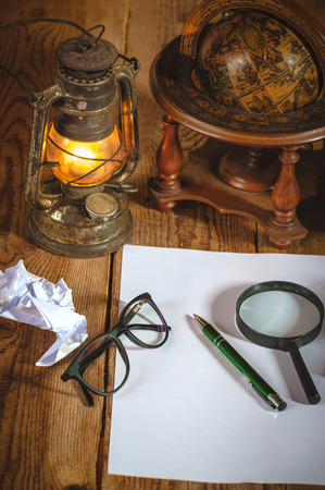 Vintage still life stuff on a rustic wooden table,retro camera, glasses, pencil, pen, old rusty kerosene lamp.の写真素材