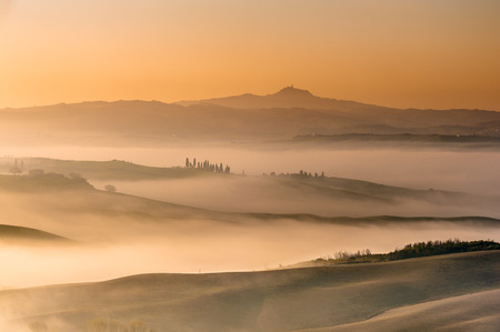 Mist flowing in the green fields of Tuscany in the morningの写真素材