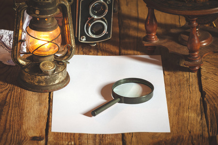 Vintage still life stuff on a rustic wooden table,retro camera, glasses, pencil, pen, old rusty kerosene lamp.の写真素材