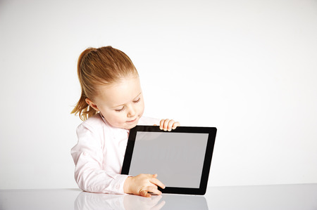 Cute little and smiling girl plays with a tabletの写真素材